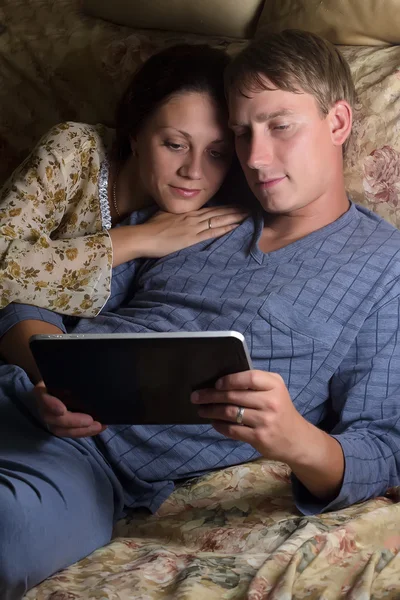 Šťastný pár seděli spolu na pohovce, pomocí počítače tablet pc Stock Snímky