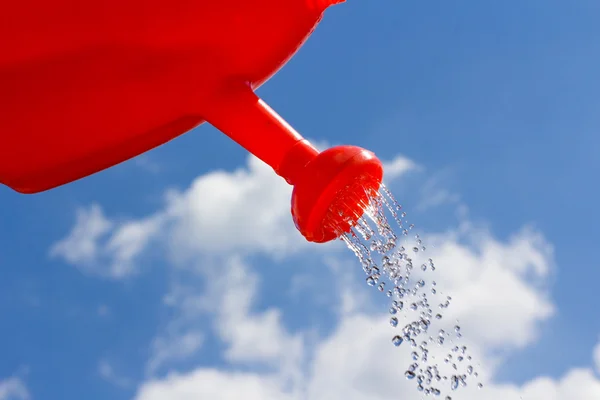 Konev nalévání vody proti obloze — Stock fotografie