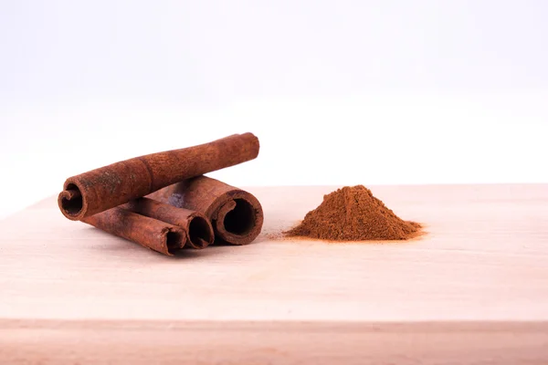 Rå och pulver cinamon på träbord — Stockfoto