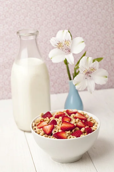 Bowl of cereal with strawberries with bottle of milk — Stock Photo, Image