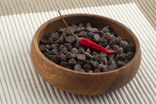 Chocolate chips and chili on the wooden bowl — Stock Photo, Image