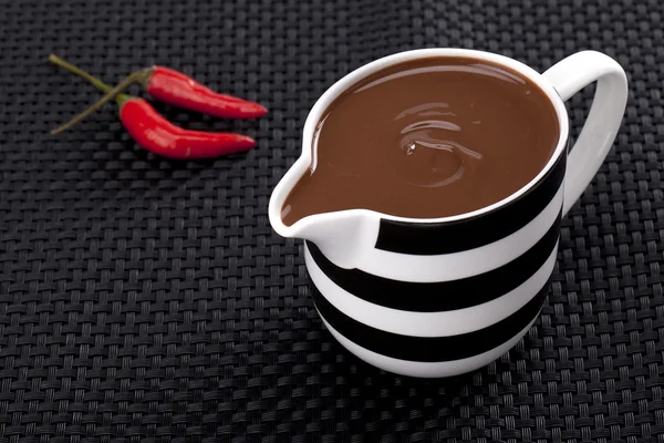 Röd chili med kopp smält choklad — Stockfoto