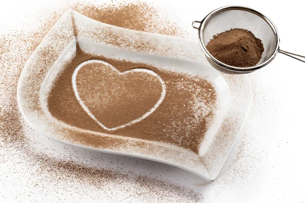 Strainer with cocoa while heart shape on a white container — Stok fotoğraf