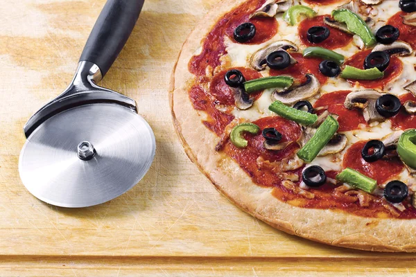 Pizza met pizza cutter — Stockfoto