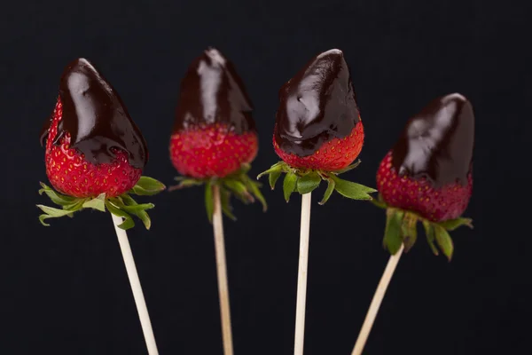 四个草莓与熔化的巧克力对黑暗 — 图库照片