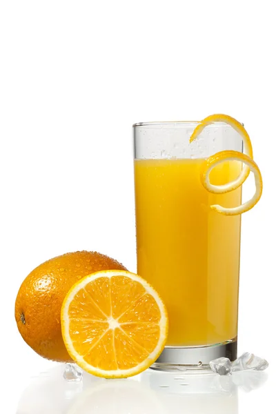 Стекло апельсинового сока с апельсиновой шелухой рядом с апельсинами — стоковое фото