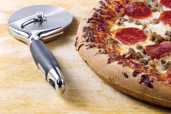 Pizza cutter and pizza — Stock Photo, Image