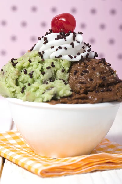 Uma tigela com chocolate e sorvete de hortelã e cereja no topo — Fotografia de Stock