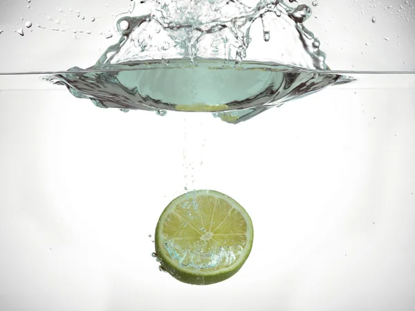 Metade do fruto de limão salpicando na água — Fotografia de Stock