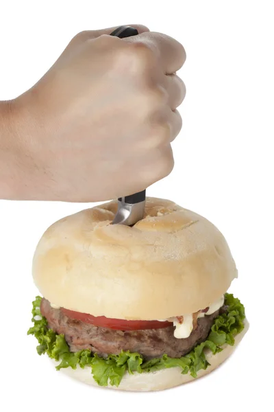Hand sticht auf einen Hamburger ein — Stockfoto