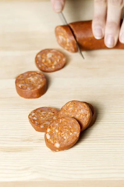 Hand cutting sausage — Stock Photo, Image