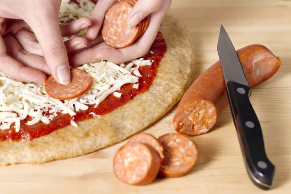 Colocando salsicha de fatia em uma pizza — Fotografia de Stock