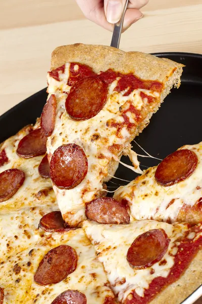 Plocka en bit pepperoni pizza — Stockfoto