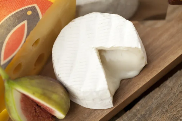 Plátek sýra a fík na dřevěné desce — Stock fotografie