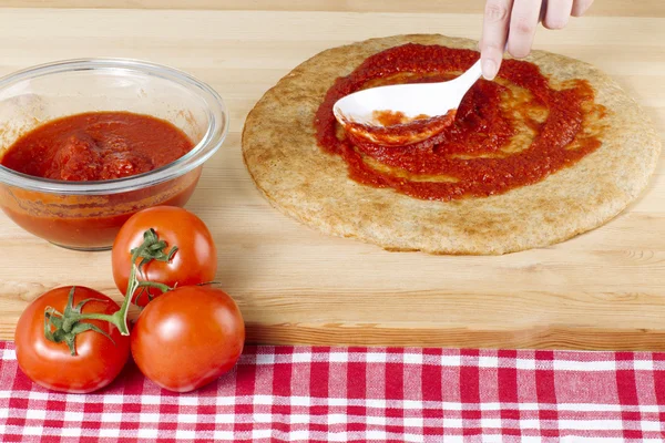 Sprida tomatsås på en pizzadeg — Stockfoto