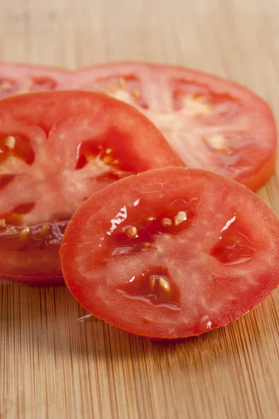 Slices of fresh tomatoes on the wooden table — Stock Photo, Image