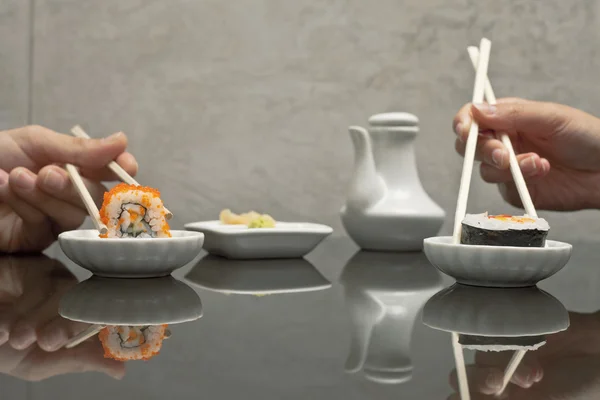 Hände halten Sushi mit Stäbchen im Restaurant Stockbild