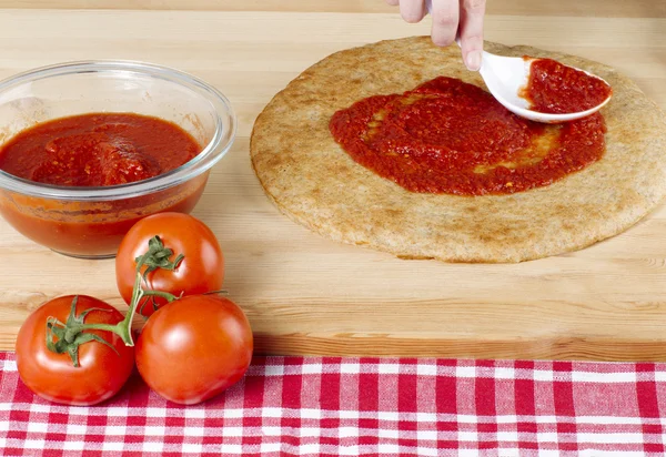 Pizzateig mit roter Sauce und Tomaten Stockbild