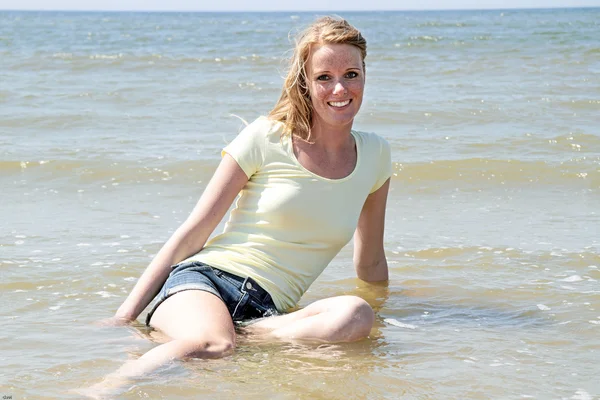 Schöne Frau, die im Wasser des Ozeans sitzt — Stockfoto