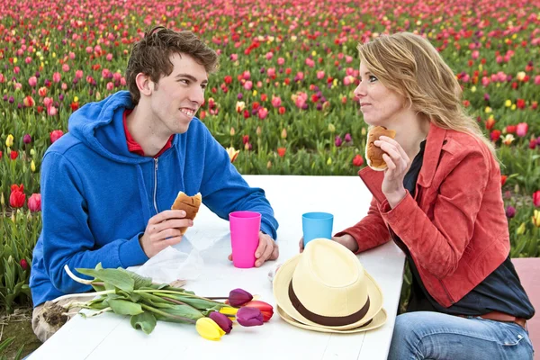 Junges Paar beim Mittagessen zwischen den Tulpen — Stockfoto