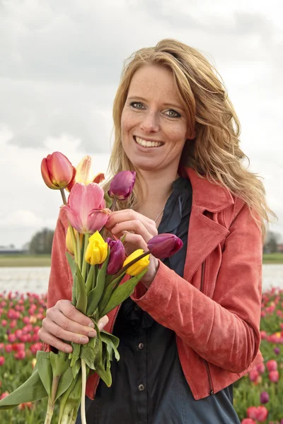 Hermosa mujer con tulipanes en los campos — Foto de Stock