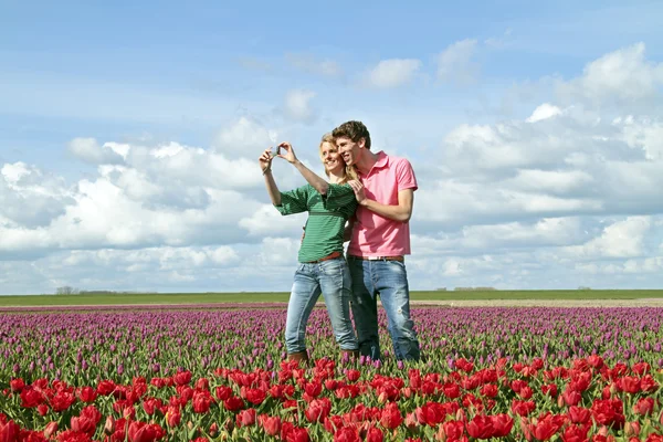Unga lyckliga par att göra en bild i fälten tulip — Stockfoto