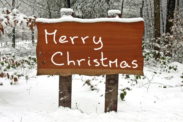 Frohe Weihnachten im Winter auf ein verschneites Holzschild geschrieben — Stockfoto
