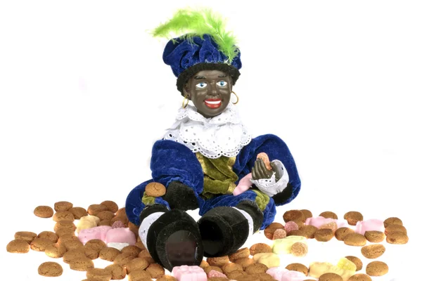 Schwarzer Piet sitzt auf einer Tüte mit Ingwernüssen und Bonbons — Stockfoto