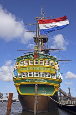 VOC ship in Amsterdam harbor the Netherlands with the dutch national flag clipart