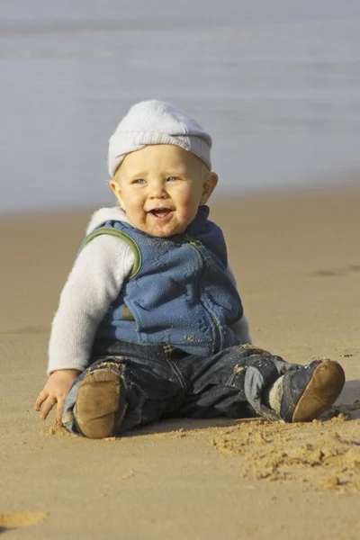 Cute little baby boy sitting and laughing at the beach — Stock Photo, Image