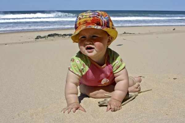 Söt liten baby flicka sitter i sanden på stranden — Stockfoto