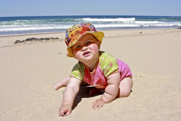 Ładny mała dziewczynka siedzi w piasku na plaży — Zdjęcie stockowe
