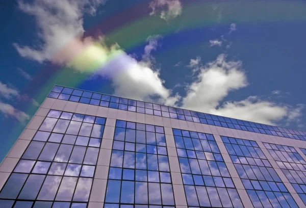 Edificio de vidrio en Amsterdam Países Bajos con un arco iris en el cielo — Foto de Stock