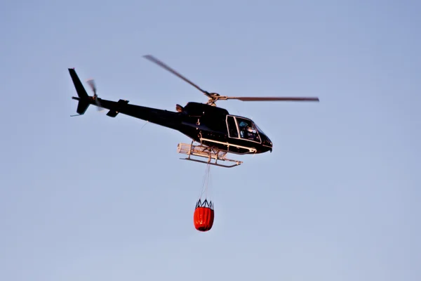 Fire fighting helicopter with waterbag on his way to combat the forest fire — Stock Photo, Image