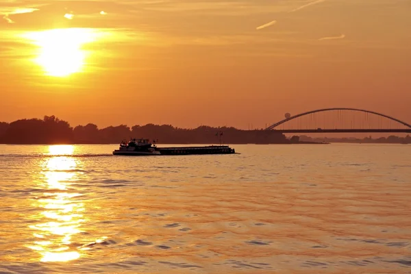 stock image Freighter cruising on the river Merwede with the Moerdijkbrug in the Netherlands at sunset