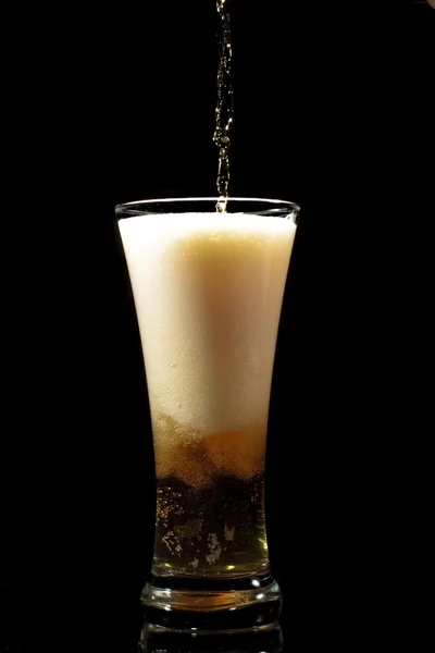Birra versata in vetro su fondo nero — Foto Stock