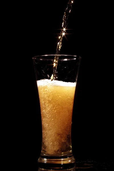 Bière versant dans le verre sur un fond noir — Photo
