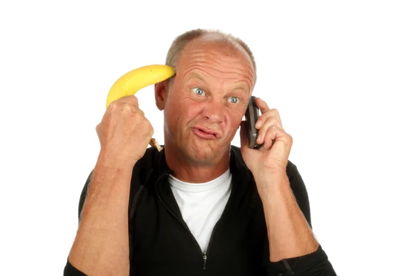 绝望的男人打电话时指向他香蕉用枪指着他的头 — 图库照片