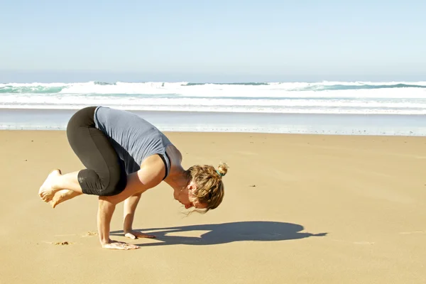 Giovane donna sana che fa esercizi di yoga in spiaggia — Foto Stock