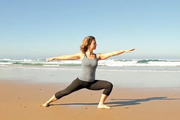Ung frisk kvinna gör yogaövningar på stranden — Stockfoto