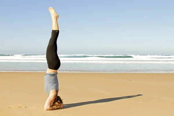 Joven mujer sana haciendo ejercicios de yoga en la playa —  Fotos de Stock