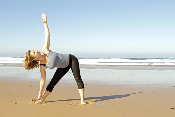 Junge gesunde Frau macht Yoga-Übungen am Strand — Stockfoto