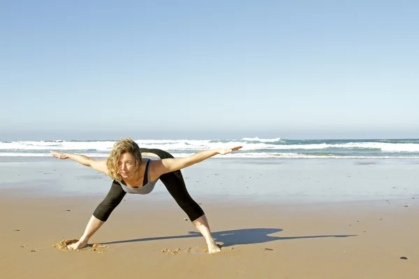 Ung frisk kvinna gör yogaövningar på stranden — Stockfoto
