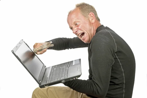 Rozhněvaný muž ničí jeho laptop s kladivem — Stock fotografie