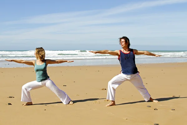 Jovem casal fazendo exercícios de ioga na praia — Fotografia de Stock
