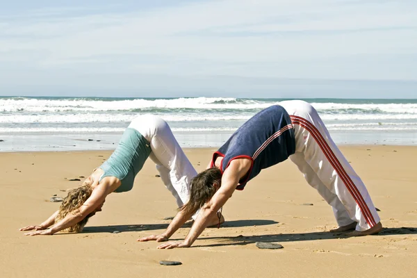Giovane coppia che fa esercizi di yoga in spiaggia — Foto Stock