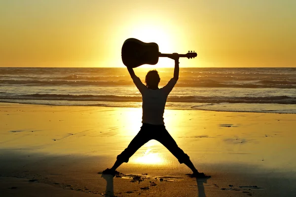 Гитарист на пляже на закате — стоковое фото