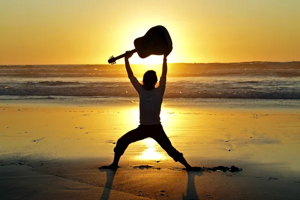Гитарист на закате на пляже — стоковое фото