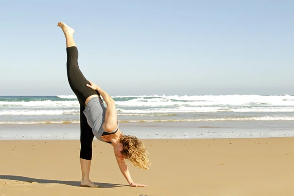 Mladá zdravá žena dělá jóga cvičení na pláži — Stock fotografie