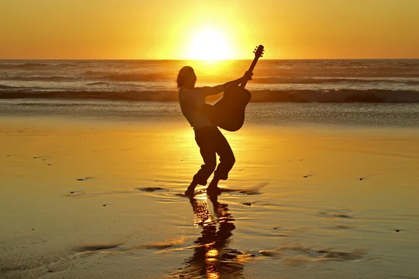 Гитарист на пляже на закате — стоковое фото